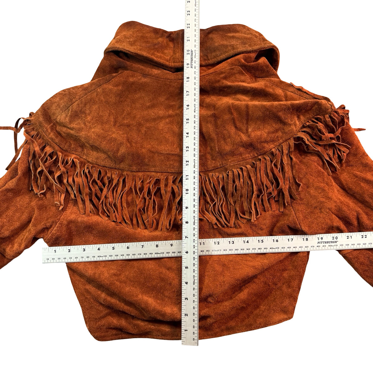 Rust suede fringe jacket laid flat with measuring tape