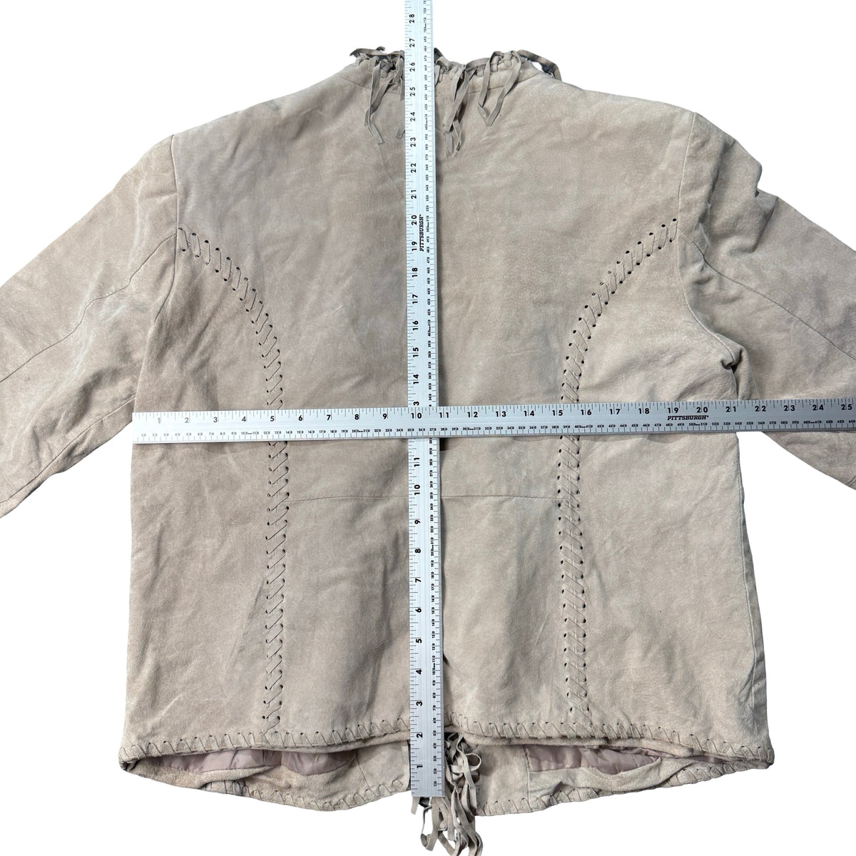 Greige suede fringe jacket laid flat with measuring tape