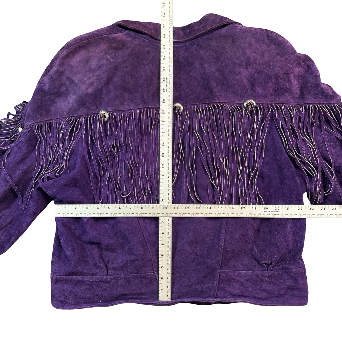 Purple suede fringe jacket laid flat with measuring tape